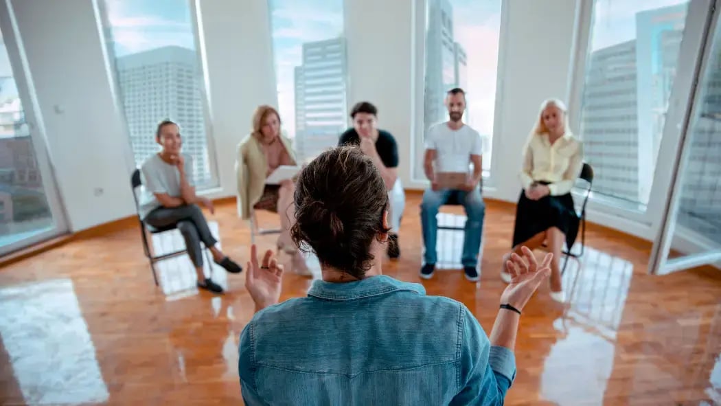 A man standing in front of a group of people talking