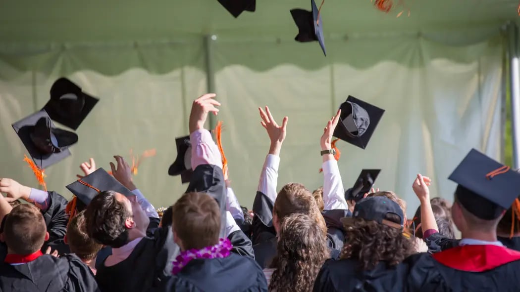 Graduates throwing graduation caps up in the air