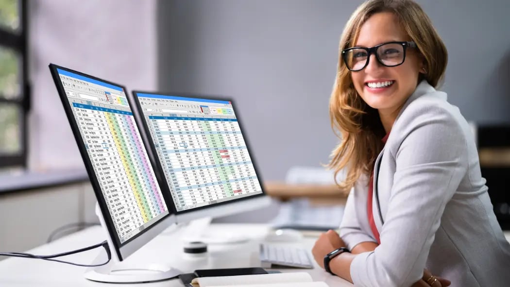 A woman sat at a computer smiling with data on the screen