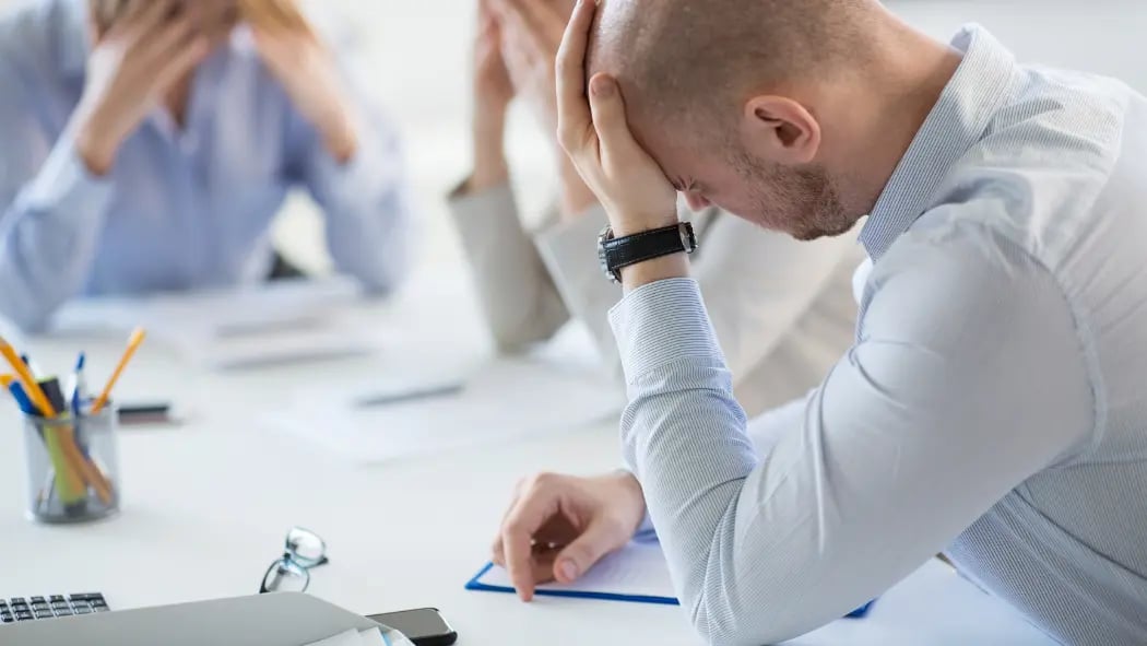 Man sat at desk with head in his hands
