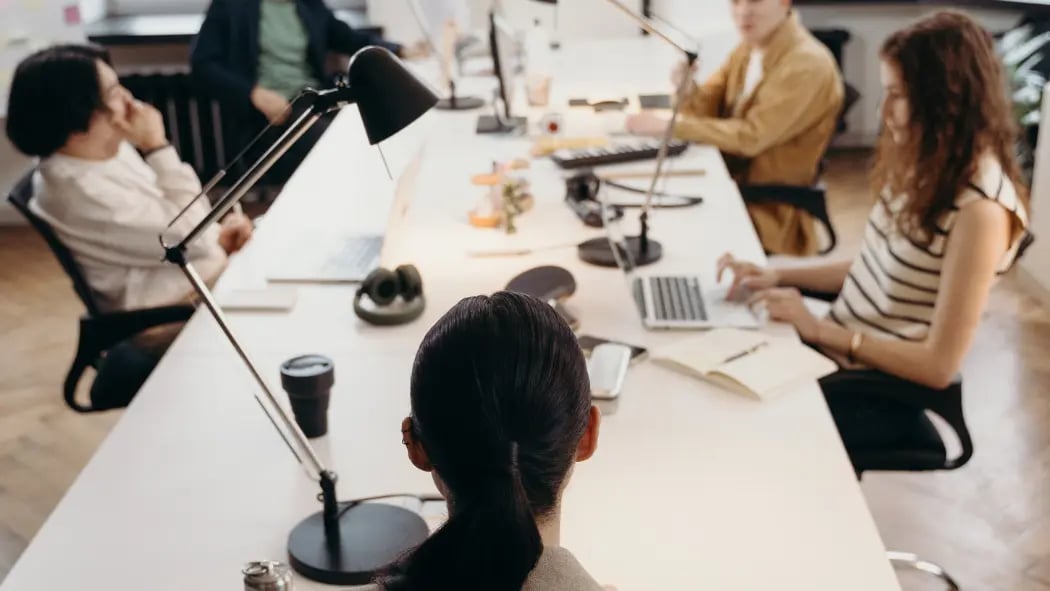 People sat around a table having a meeting with laptops in front of them