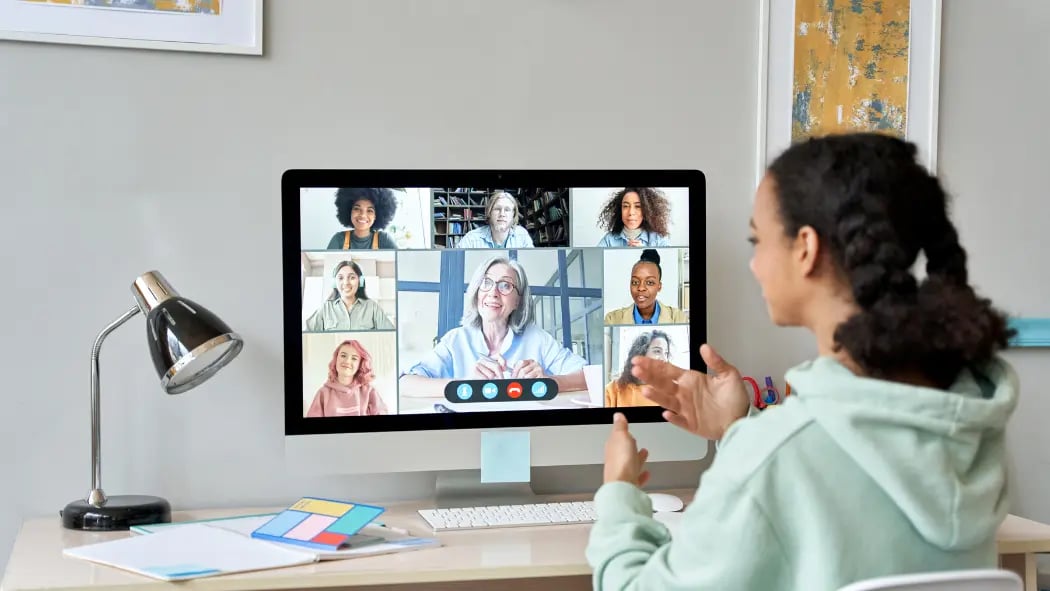 A student sat at desk in front of a computer screen taking part in a video call
