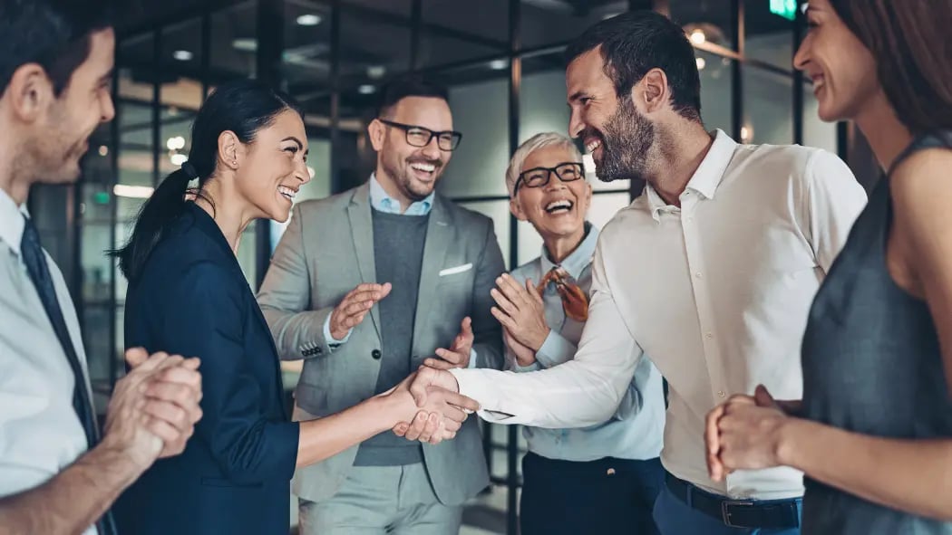 A group of people at work, with two of them shaking hands