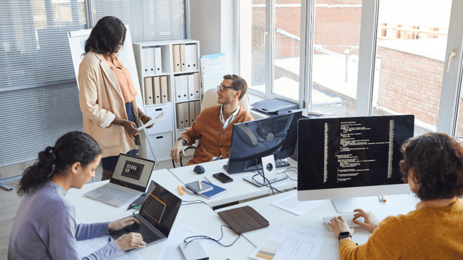 Data team sat around desk with computers 