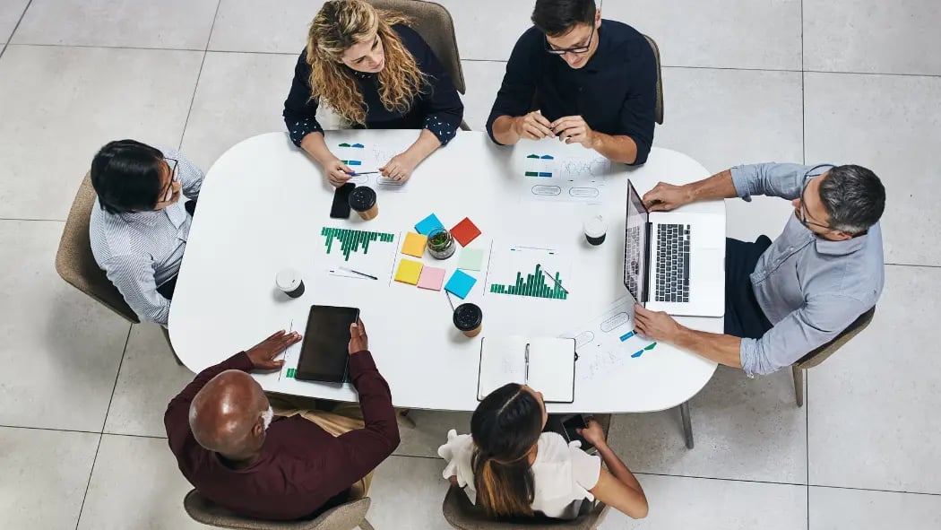 Employees sat round a meeting table looking at data