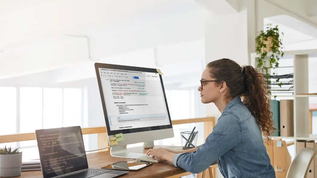 Woman sat at laptop looking at EDUKATE.AI programming software