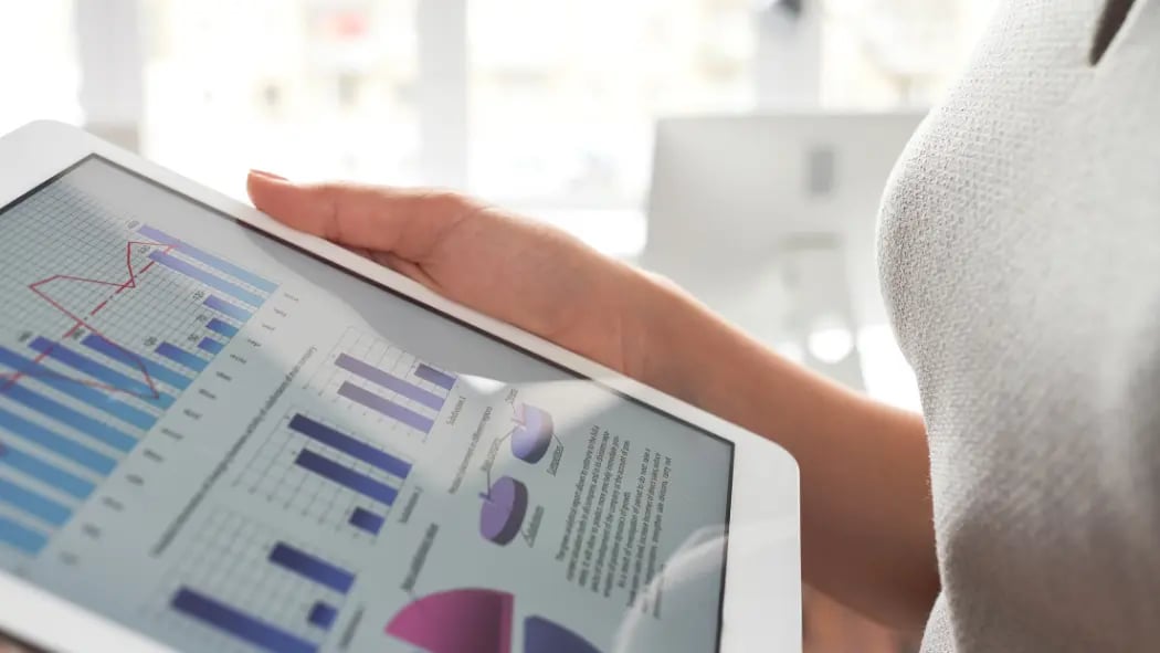 Hands holding a tablet screen showing data on it