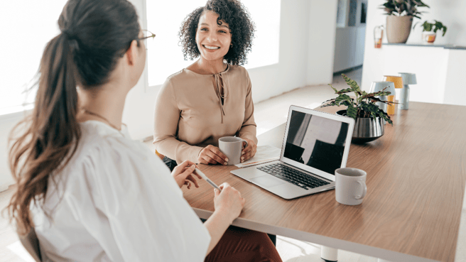 two women sat at desk in office