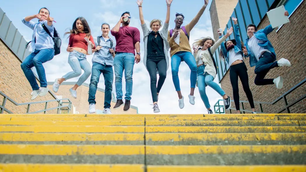 Happy students, standing in a row jumping in the air