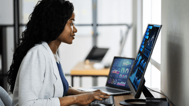 A data analyst sat a desk looking at data on a computer screen