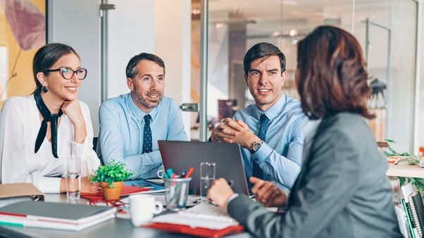 Two women and two men seated around a table in an office discussing