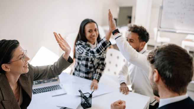 employees celebrating around meeting table