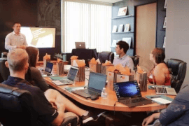 People in an office sitting around a round conference table in a meeting room