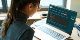 A young woman sitting in front of a laptop computer with EDUKATE.AI learning platform displayed