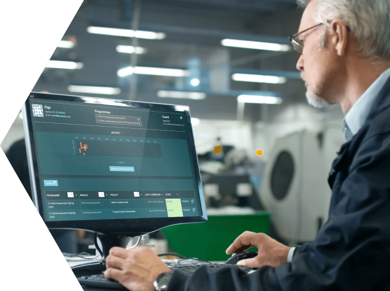 Man around 60 years old sat at a desk in an office with a computer screen showing EDUKATE.AI learning platform