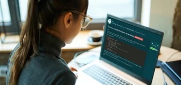 Young woman sat in front of a computer screen showing the EDUKATE.AI learning platform