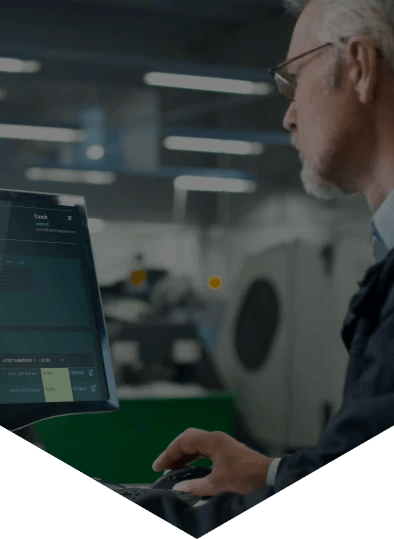 Man around 60 years old sat at a desk in an office with a computer screen showing EDUKATE.AI learning platform