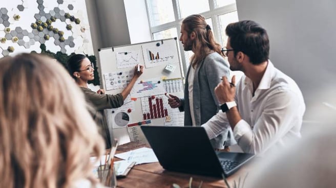 A meeting where a woman is presenting data on a board