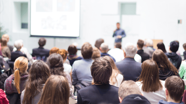 A teacher standing at the front of a lecture theatre teaching students