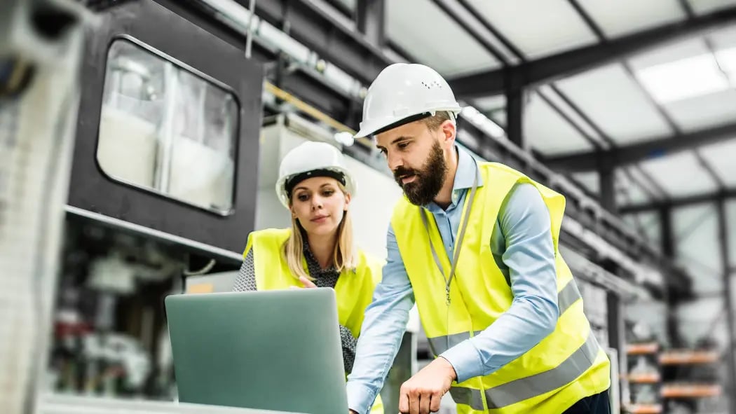 A man and woman looking at a laptop screen in a warehouse
