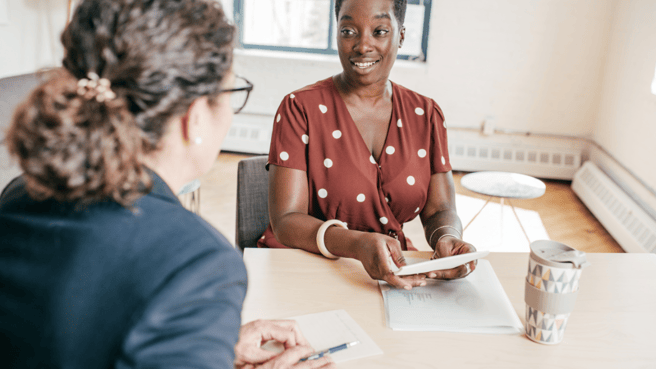 Woman mentoring an employee sat at desk