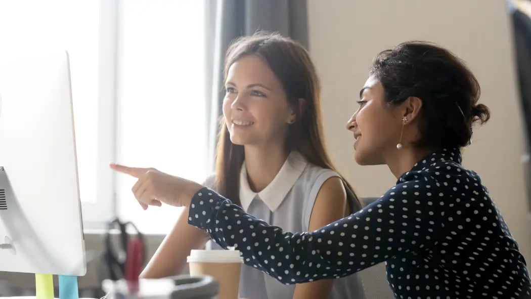 A manager and an employee sat down with manager pointing at computer screen