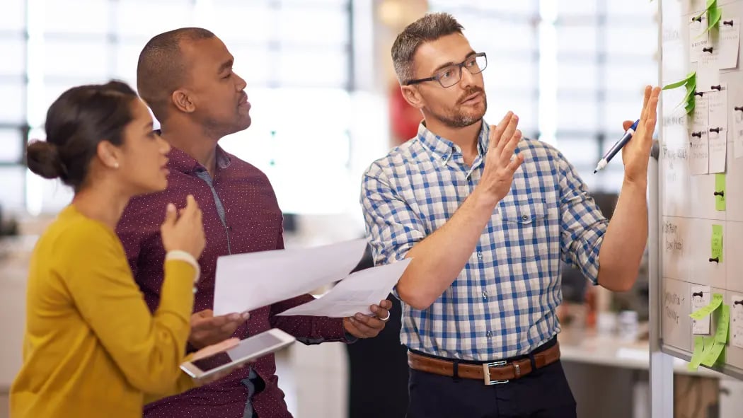 Three people in office looking at a board