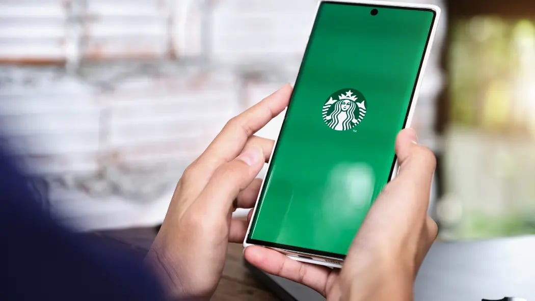 A pair of hands holding a phone showing the Starbucks app